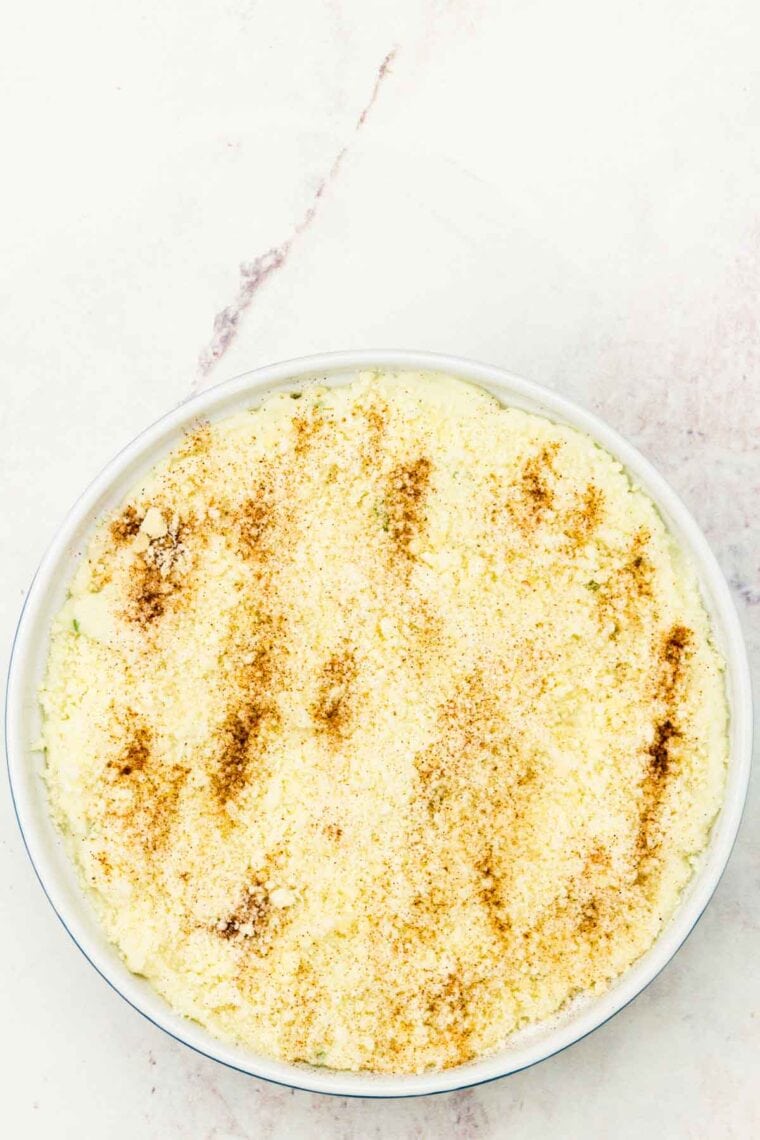 Pureed cauliflower is placed in a baking dish and topped with parmesan cheese.
