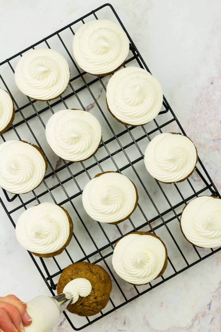 Carrot cake cupcakes are topped with cream cheese frosting.