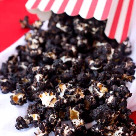 A closeup of chocolate popcorn spilling out of a red and white striped box.
