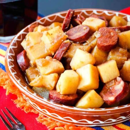 A colorful bowl of patatas riojana on a red tablecloth.