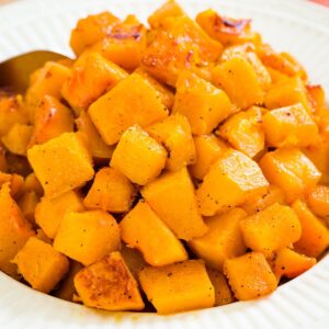 A closeup of roasted cubes of butternut squash in a bowl.