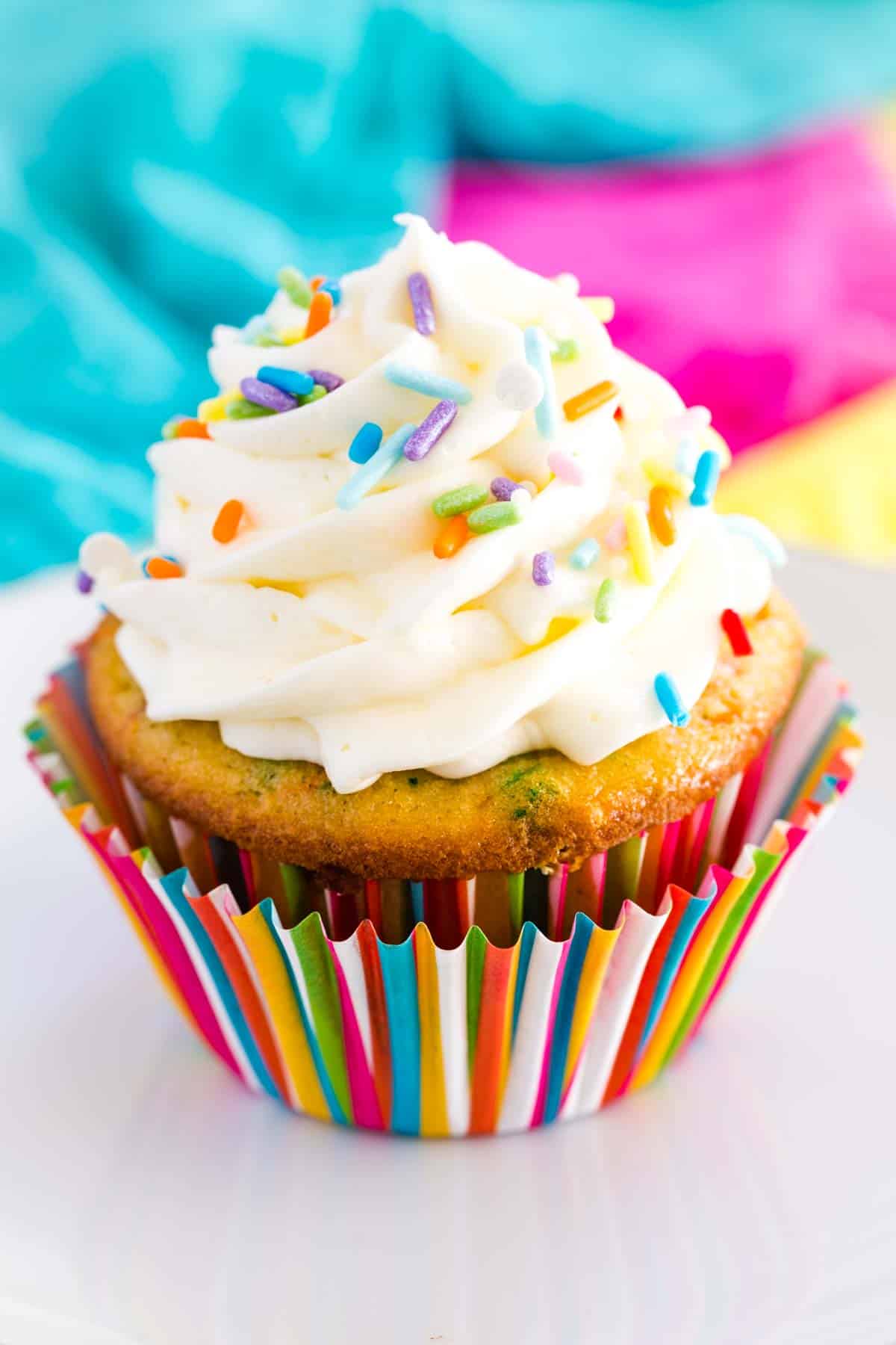 Sprinkles and vanilla frosting top a funfetti cupcake.
