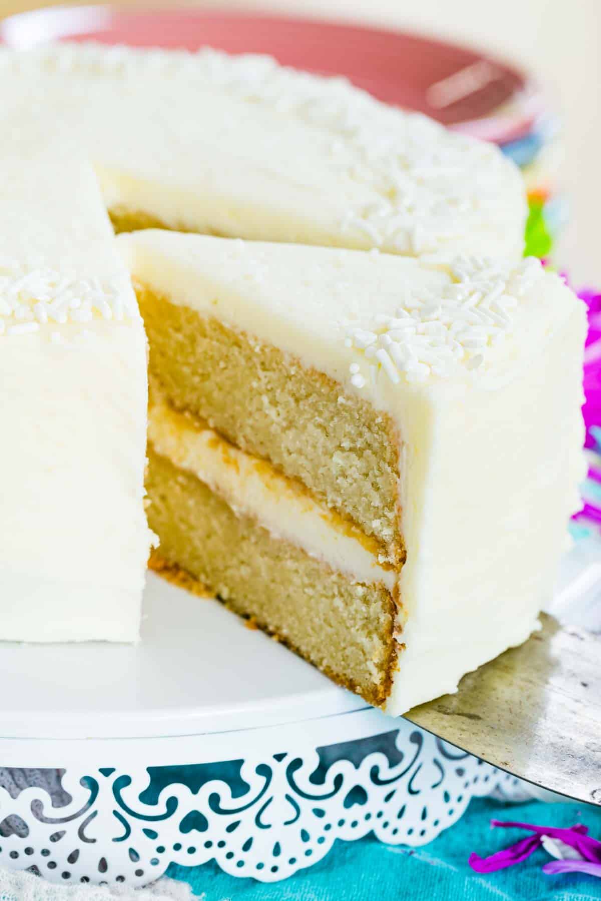 A piece of gluten free white cake is cut from the whole cake.