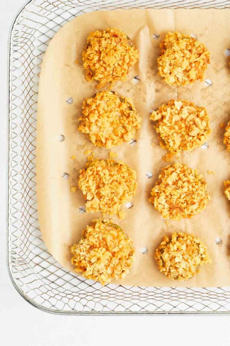 Air fryer fried pickles are arranged on a parchment-lined baking sheet.