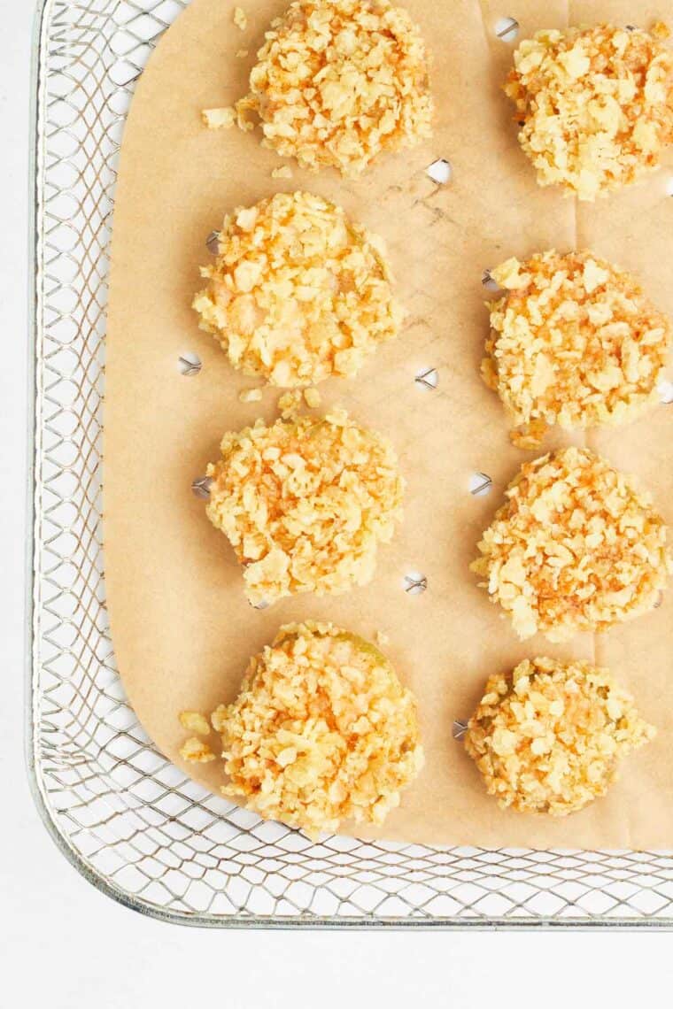 Potato chip coated pickles on a baking sheet.