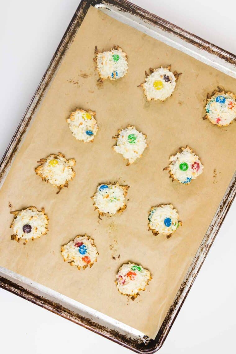 A cookie sheet with baked coconut macaroons with M&M's.
