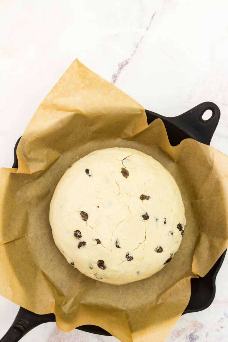 The loaf is placed in a parchment-lined cast iron pan.