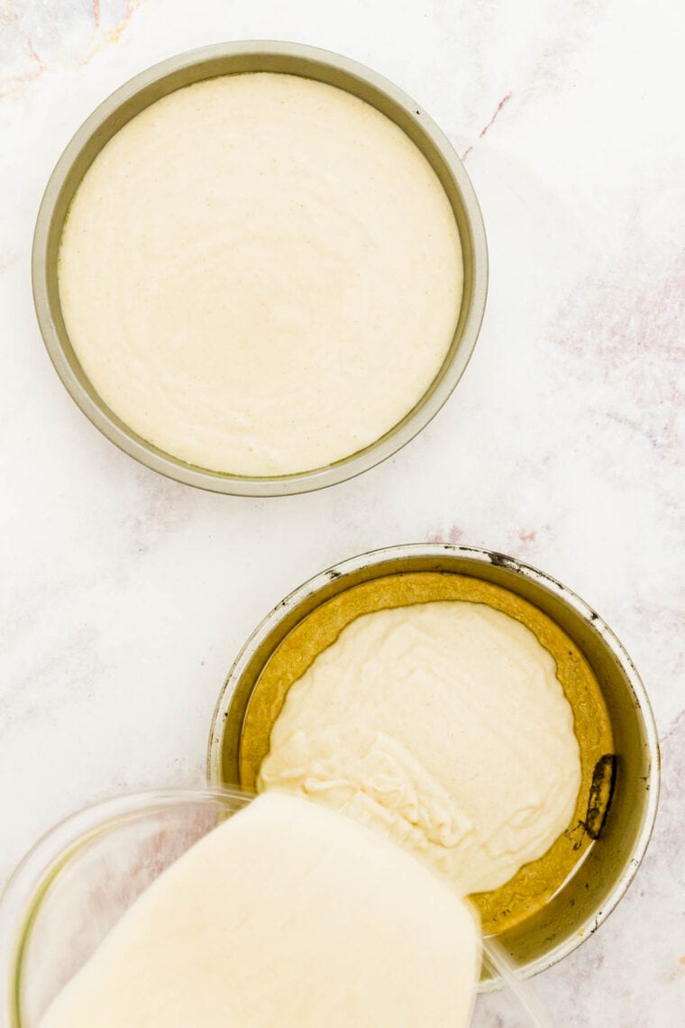 The batter is poured into two 8-inch lined cake tins.