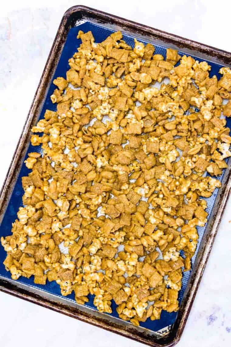 The popcorn mix is spread out evenly in a baking sheet.