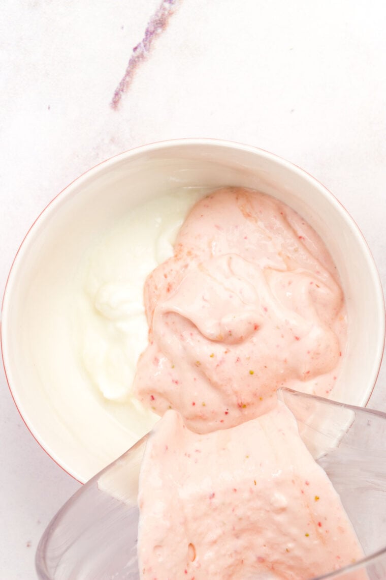 Purred strawberries are poured into Greek yogurt.