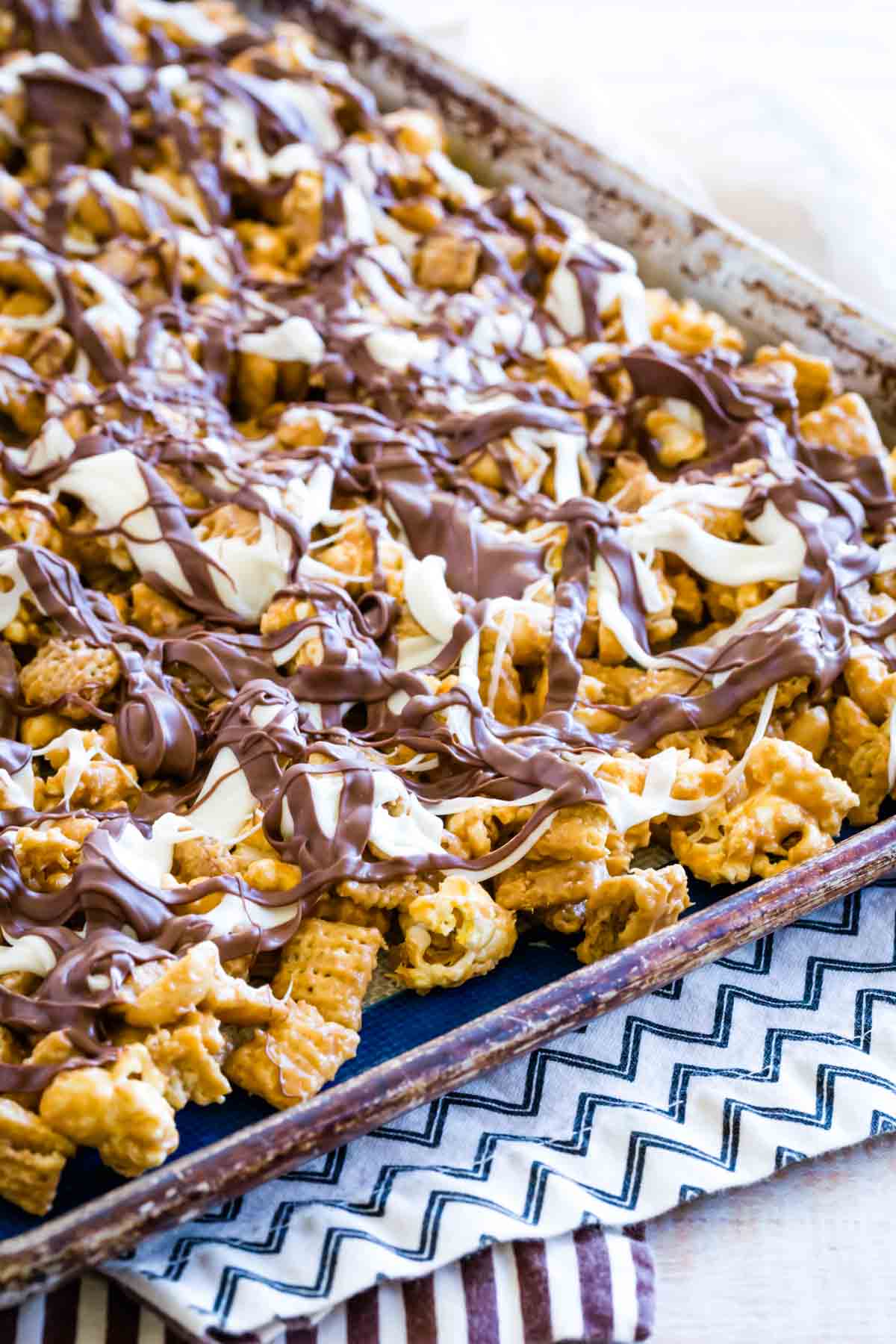 Melted chocolate tops a baking sheet filled with white chocolate popcorn.