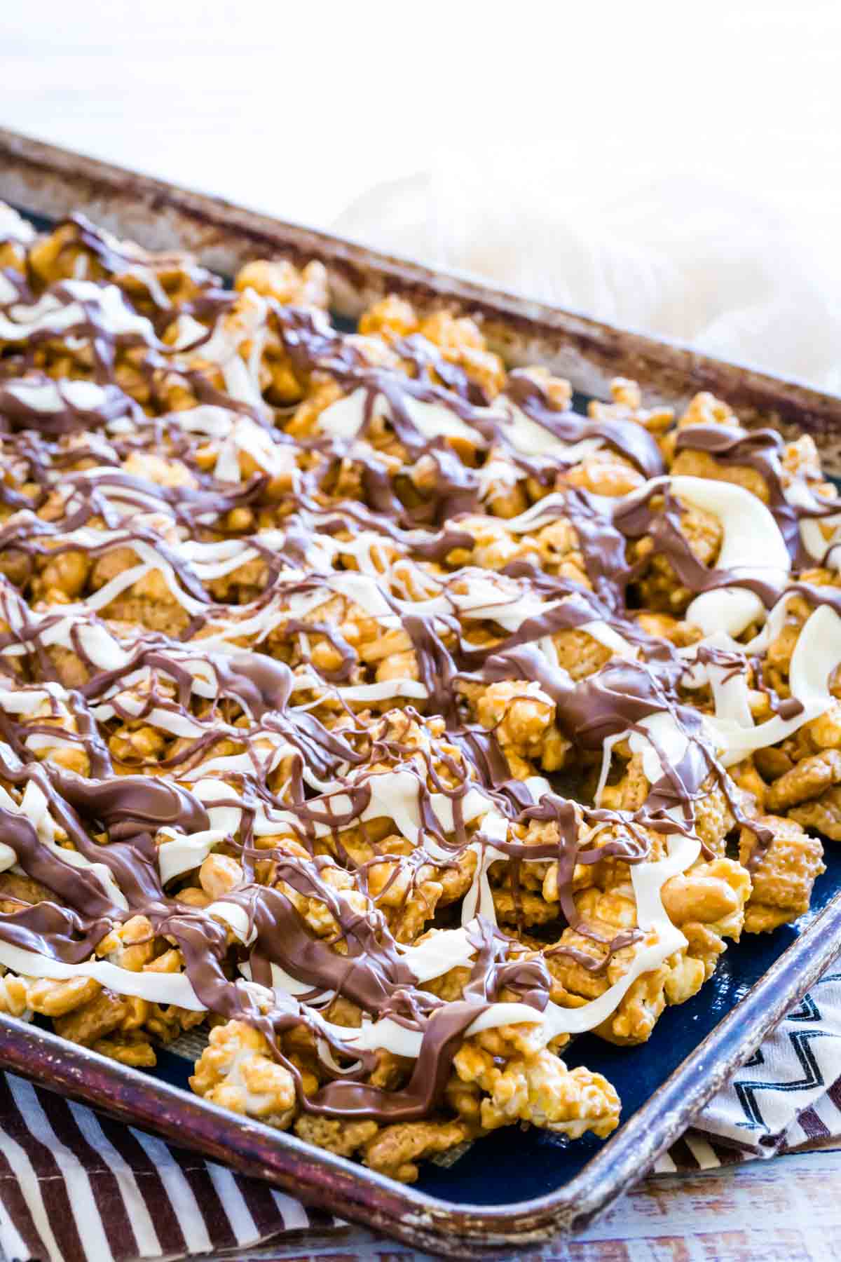 A tray of white chocolate popcorn on a striped towel.