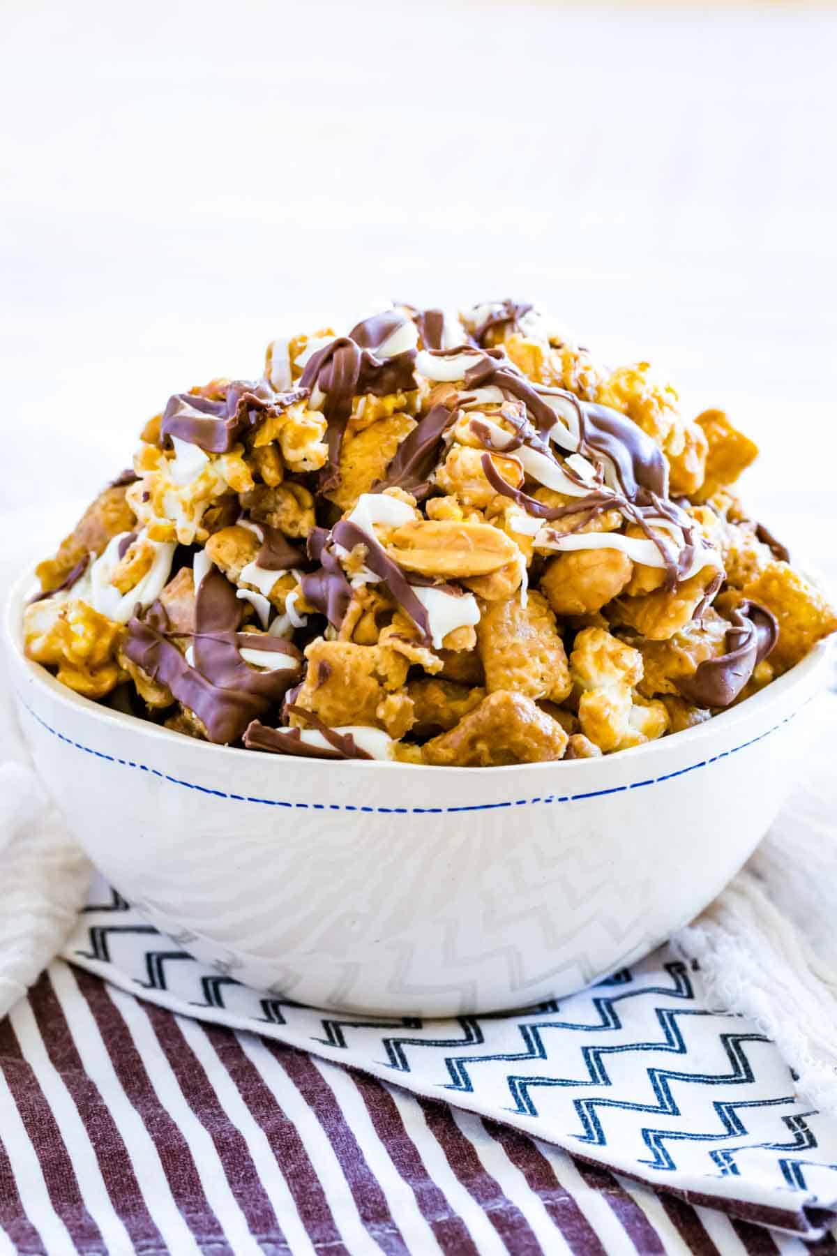 A bowl of white chocolate popcorn sits on top of a striped towel.