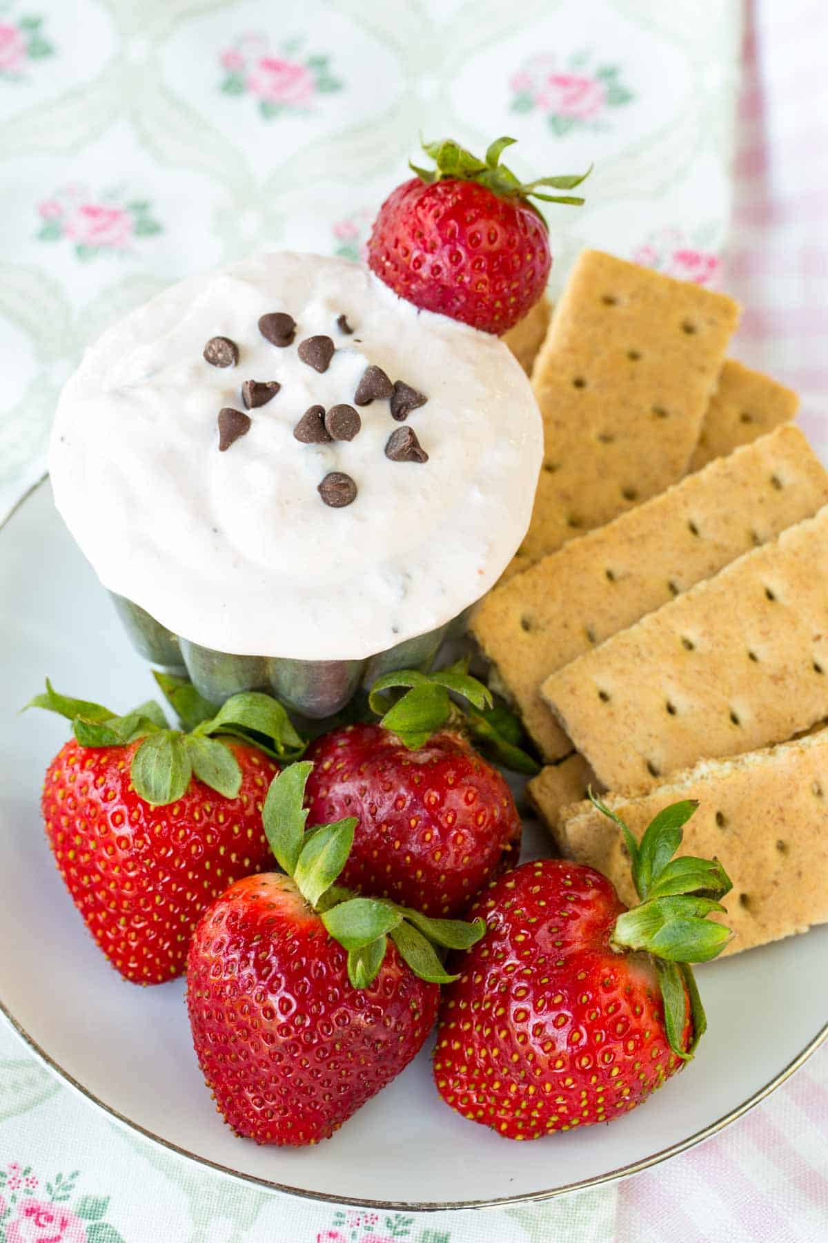 A plate of strawberries and graham crackers, plus a bowl chocolate chip-topped strawberry dip.