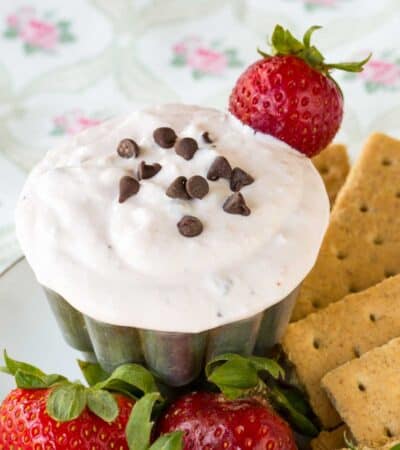 Graham crackers and fresh strawberries surround a dish of strawberry fruit dip.