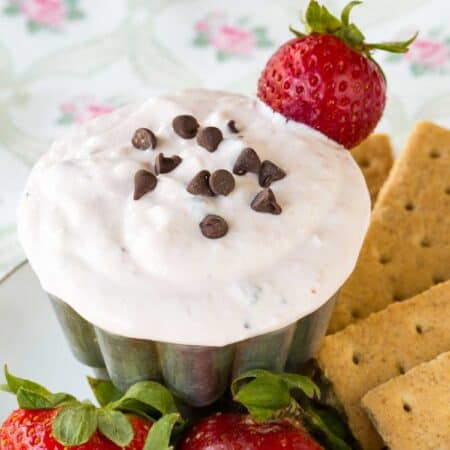 Graham crackers and fresh strawberries surround a dish of strawberry fruit dip.