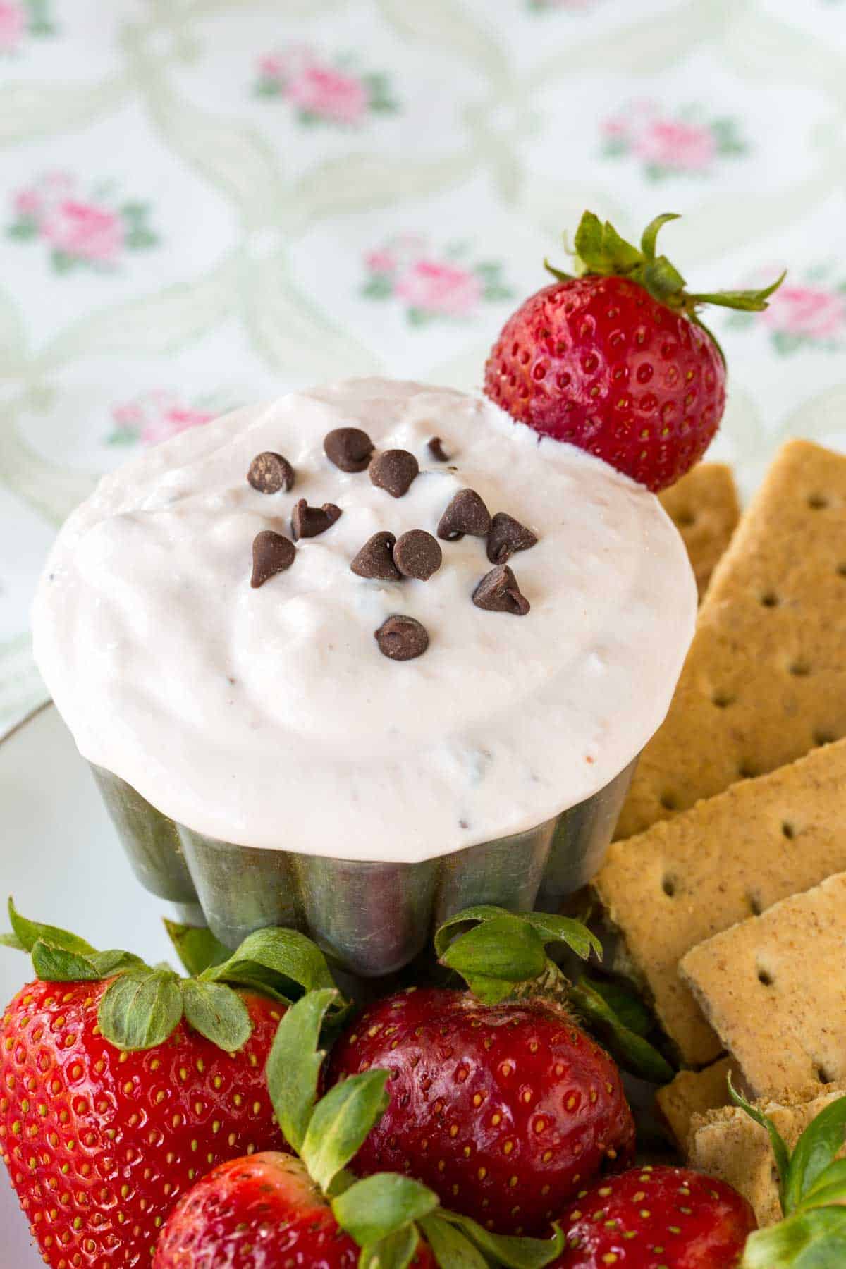 Graham crackers and fresh strawberries surround a dish of strawberry fruit dip.