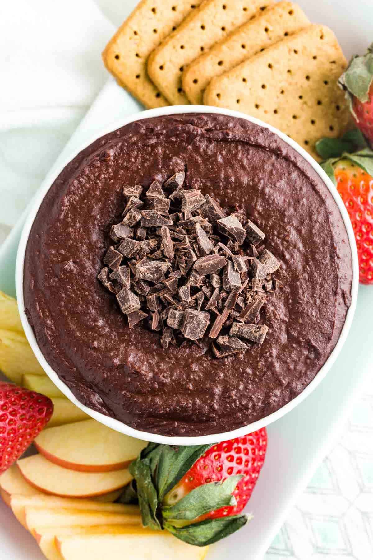 A top down view of a serving tray with cookies, strawberries, and a bowl of dark chocolate hummus.