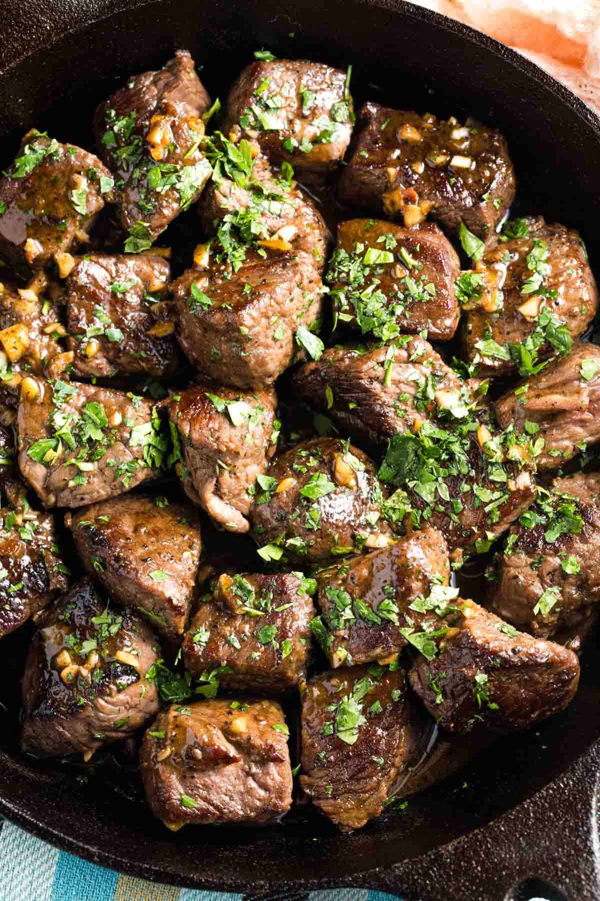 A close up of parsley-topped steak bites.