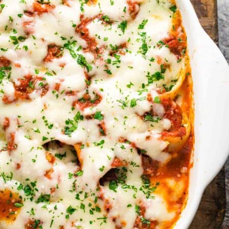 A side view of a pan of spinach stuffed shells topped with melted cheese.