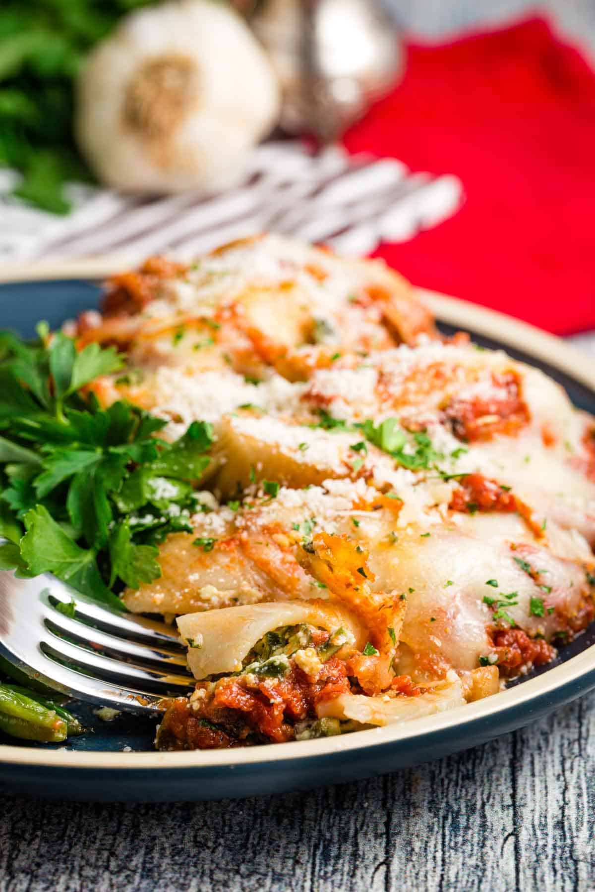 A fork digs into a plate of spinach stuffed shells.