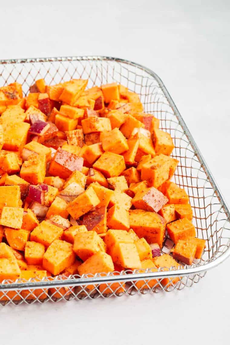 Sweet potato cubes are placed in the air fryer basket.