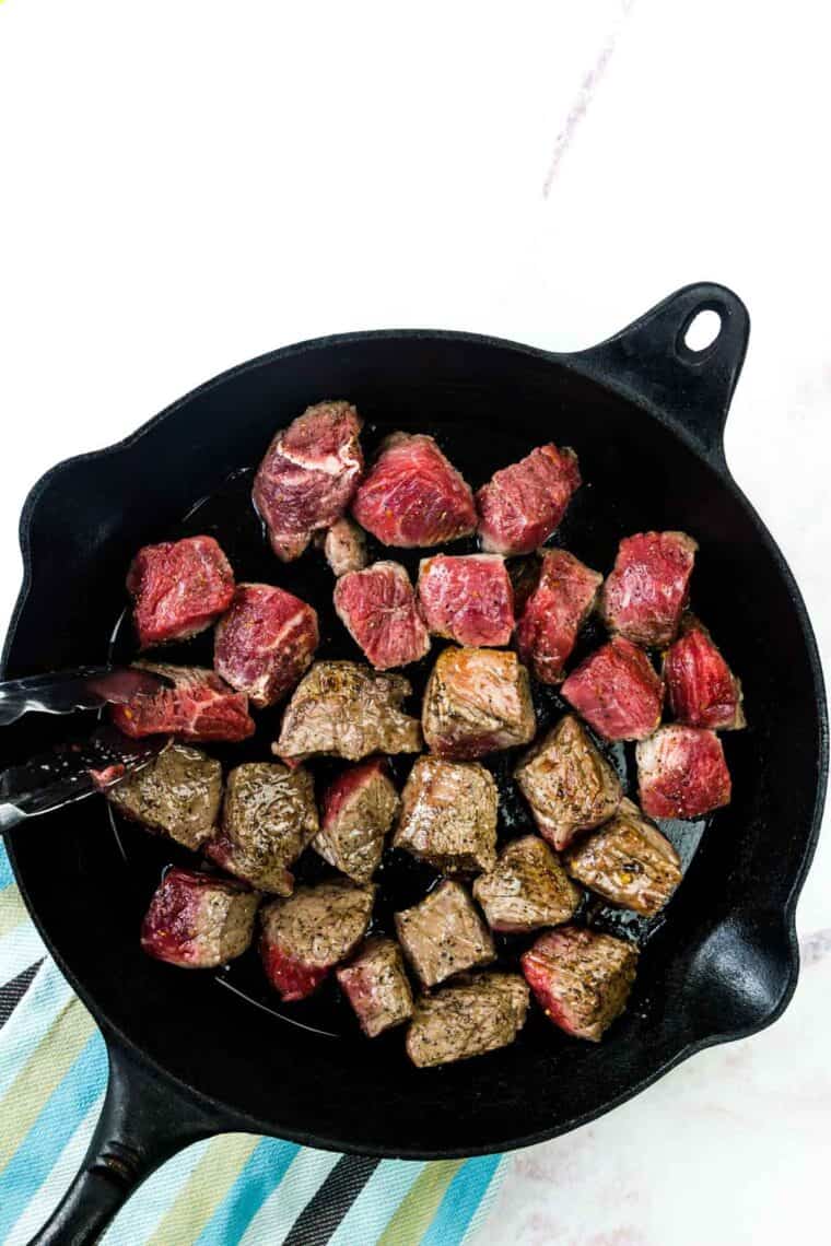 The steak cubes are flipped over to sear the other side.