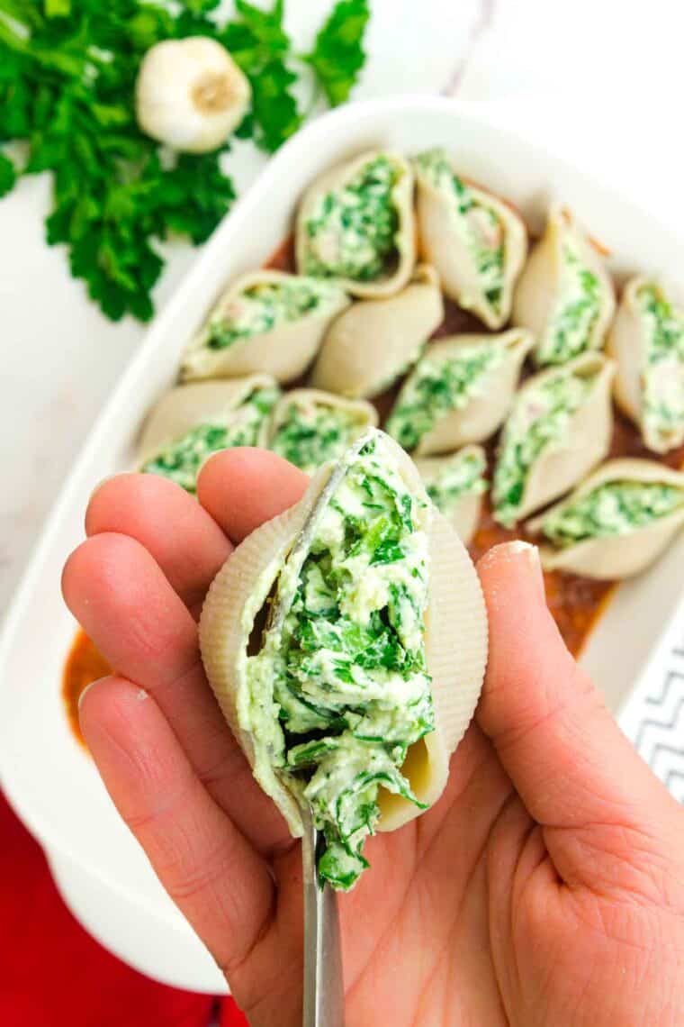 A hand shows a shelled stuffed with ricotta, ham, and spimach.