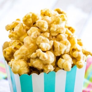 Peanut butter butterscotch popcorn overflowing over the top of a striped cardboard box.