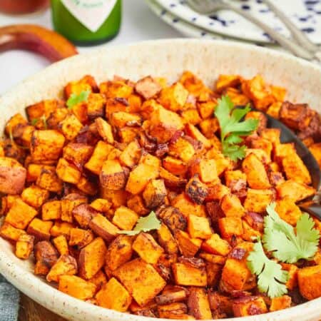 A side view of a big bowl of spicy air fryer sweet potato cubes.