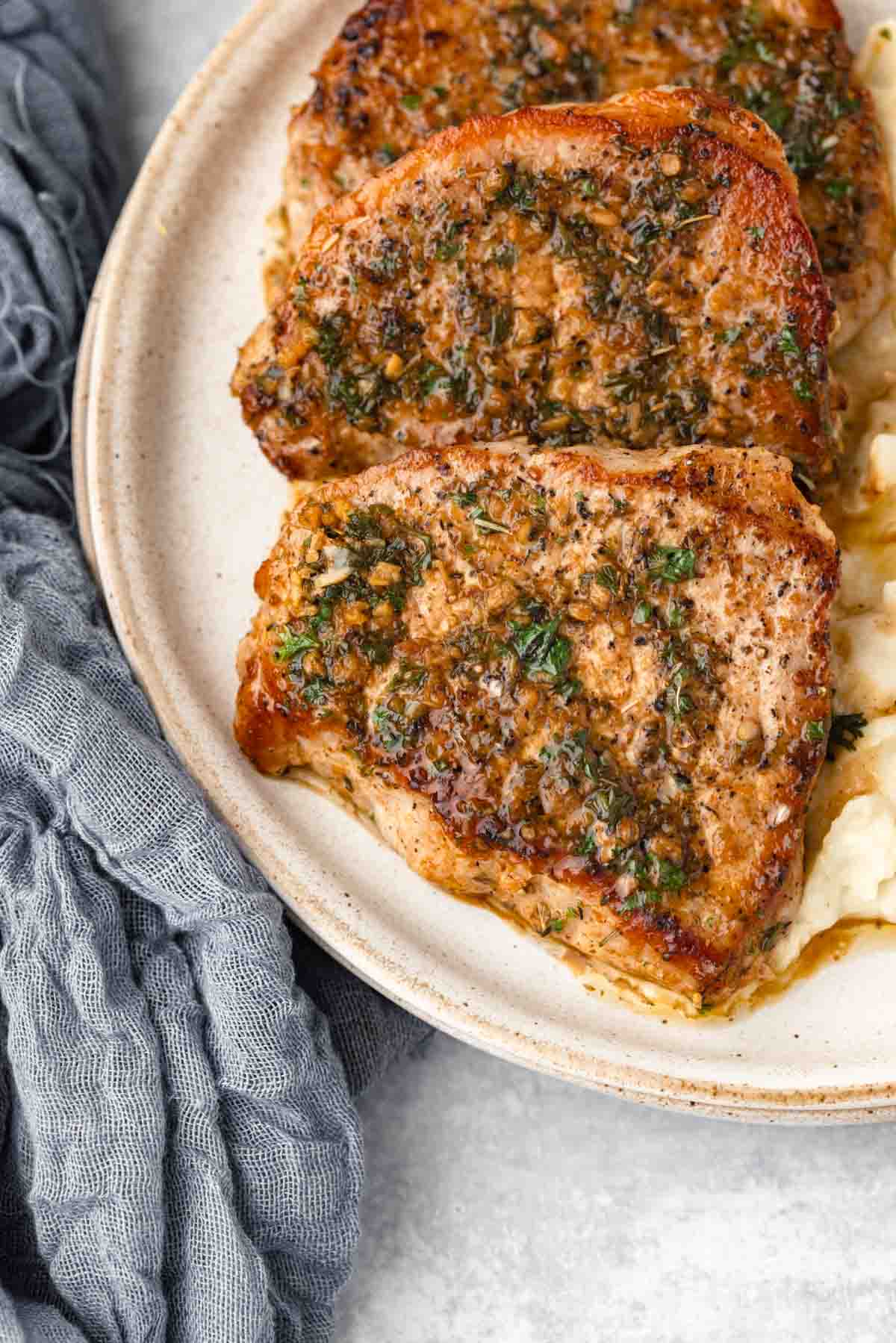 Pieces of garlic butter pork chops are arranged on a plate.