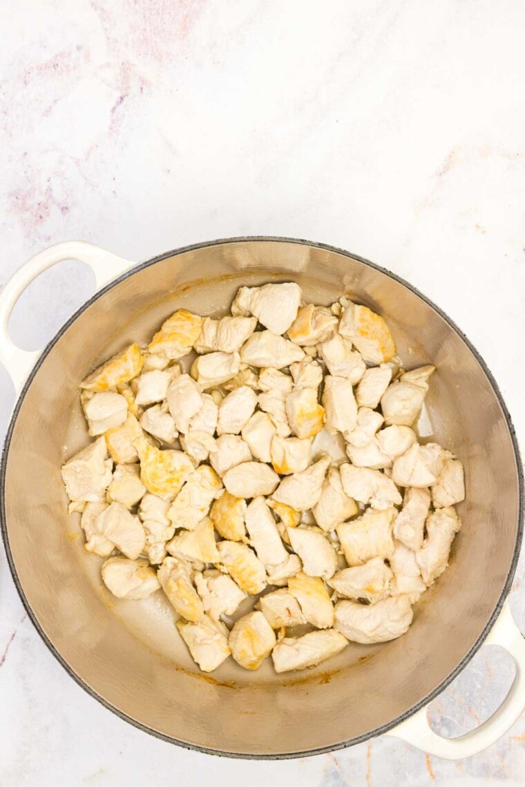 Pieces of chicken are added to a pot.