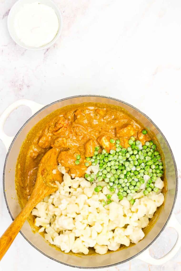 Frozen peas and cauliflower are added to the curry pot.