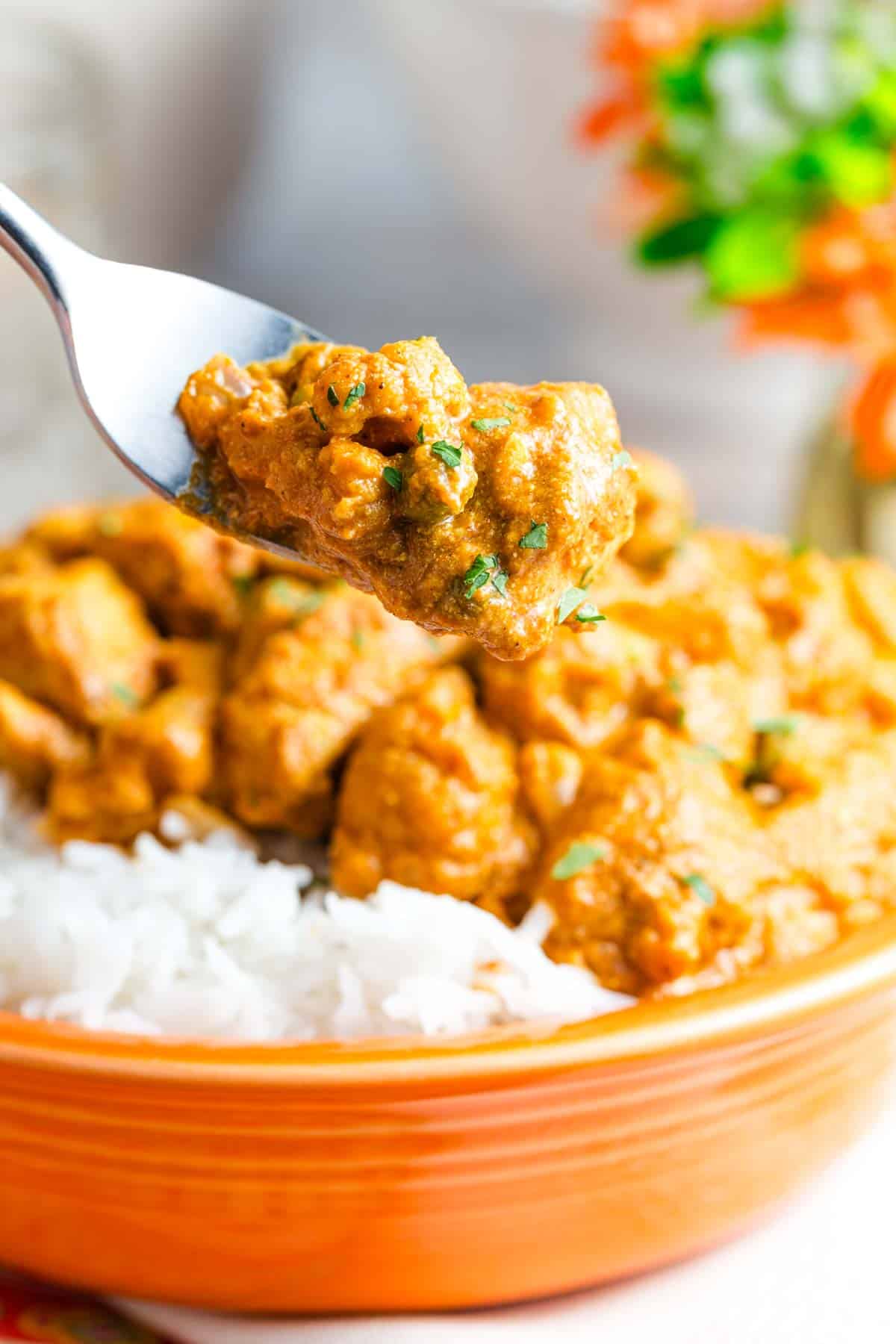 A fork lifts up a bite of quick chicken curry from a bowl of rice and curry.