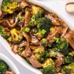 An oval white serving dish full of beef and broccoli.