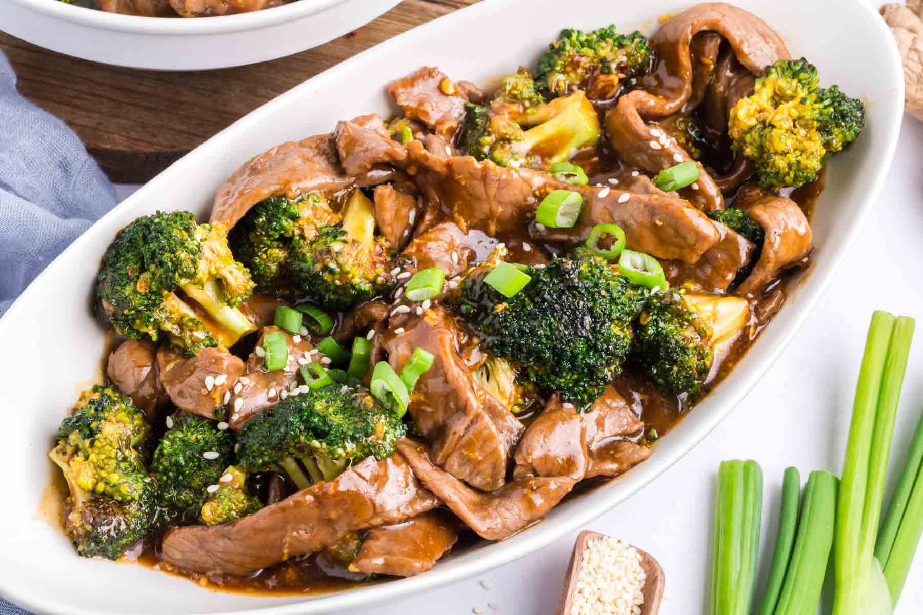 An oval white serving dish full of beef and broccoli.