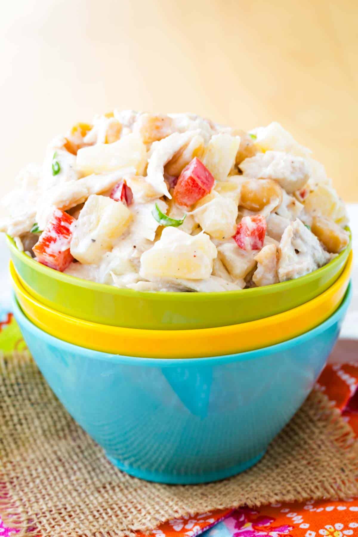 Pineapple chicken salad is served in a stack of multicolored bowls.