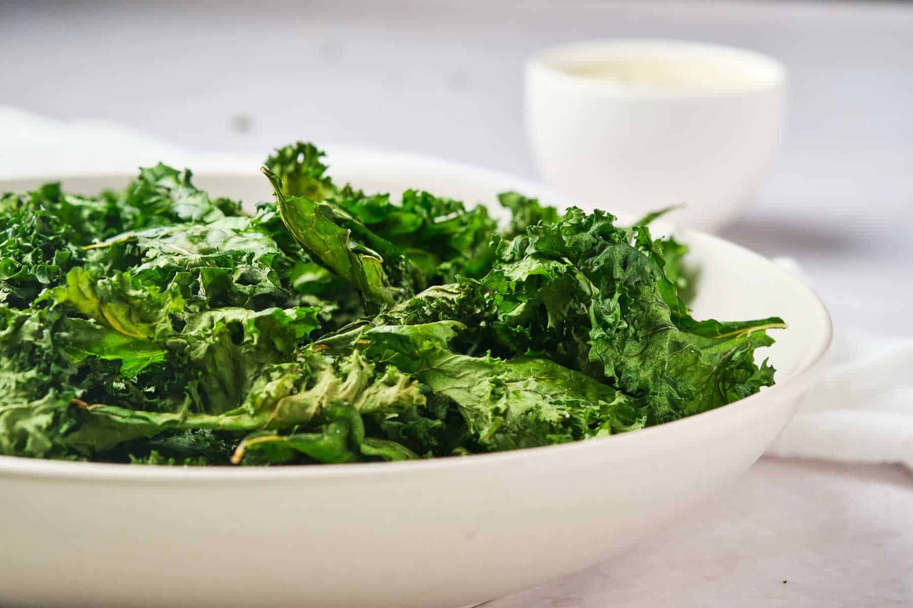 A bowl of air fryer kale chips and sauce.