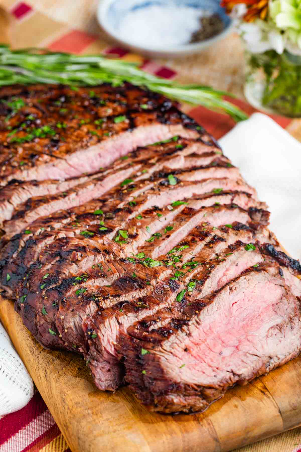 Pink slices of marinated flank steak on a cutting board.