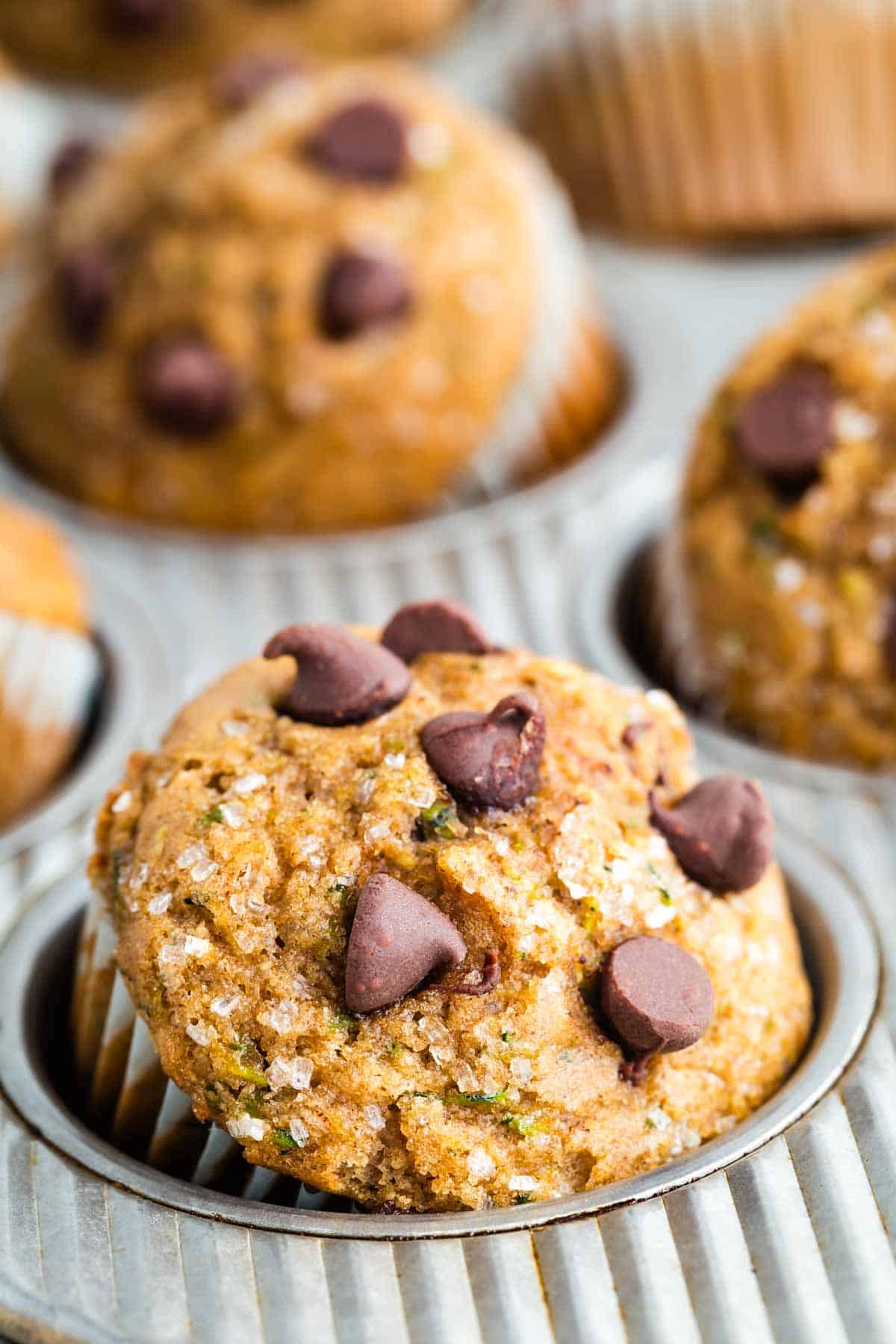 A gluten free zucchini muffin topped with chocolate in a muffin tin.