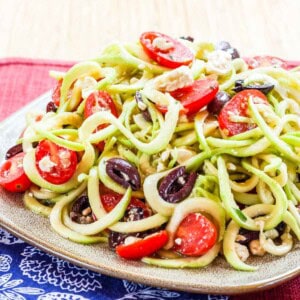 A plate of Greek zoodle salad dressed with lemon dressing.