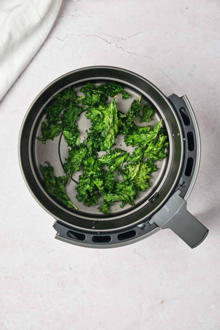 The kale cooks in the air fryer basket.