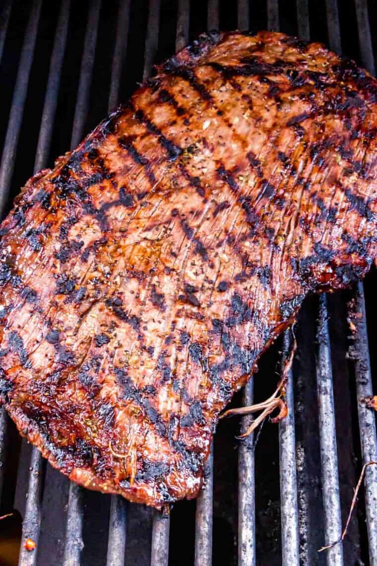 A piece of flank steak on the grill showing grill marks.