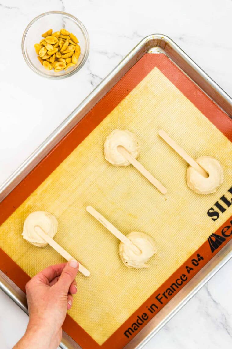 Popsicle sticks are added to the yogurt mixture on a baking sheet.