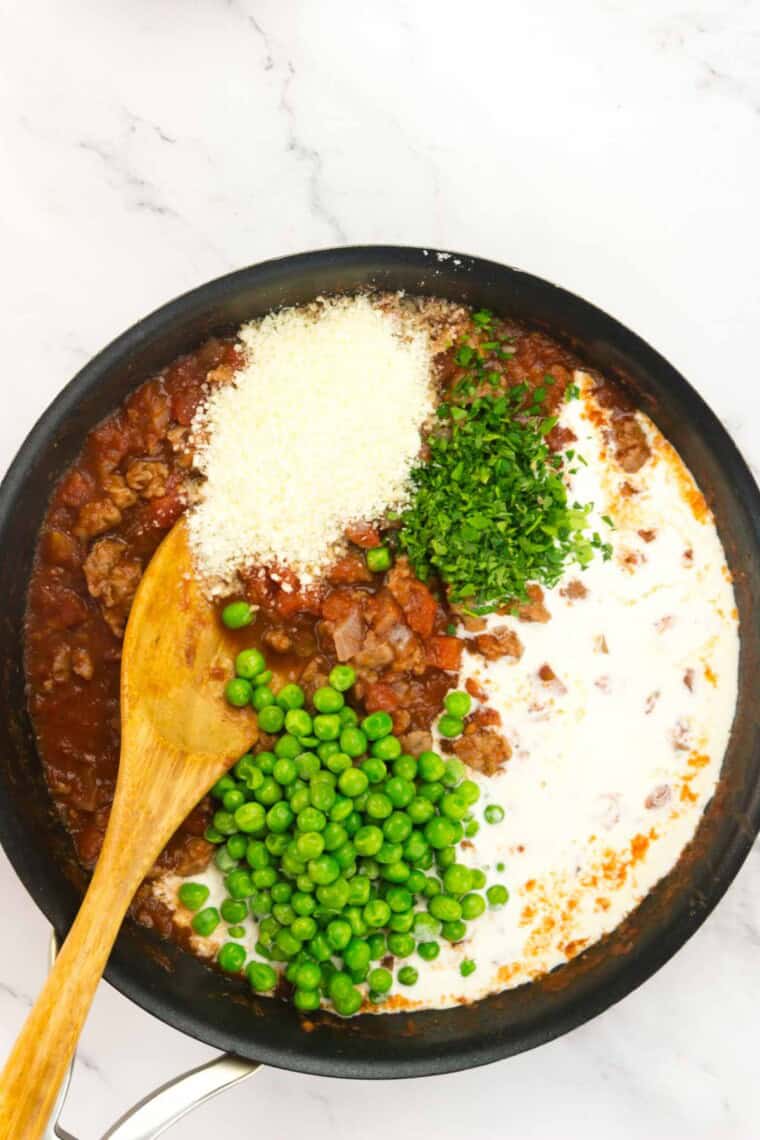 Peas, parmesan, and parsle resting on top of the skillet of sauce.