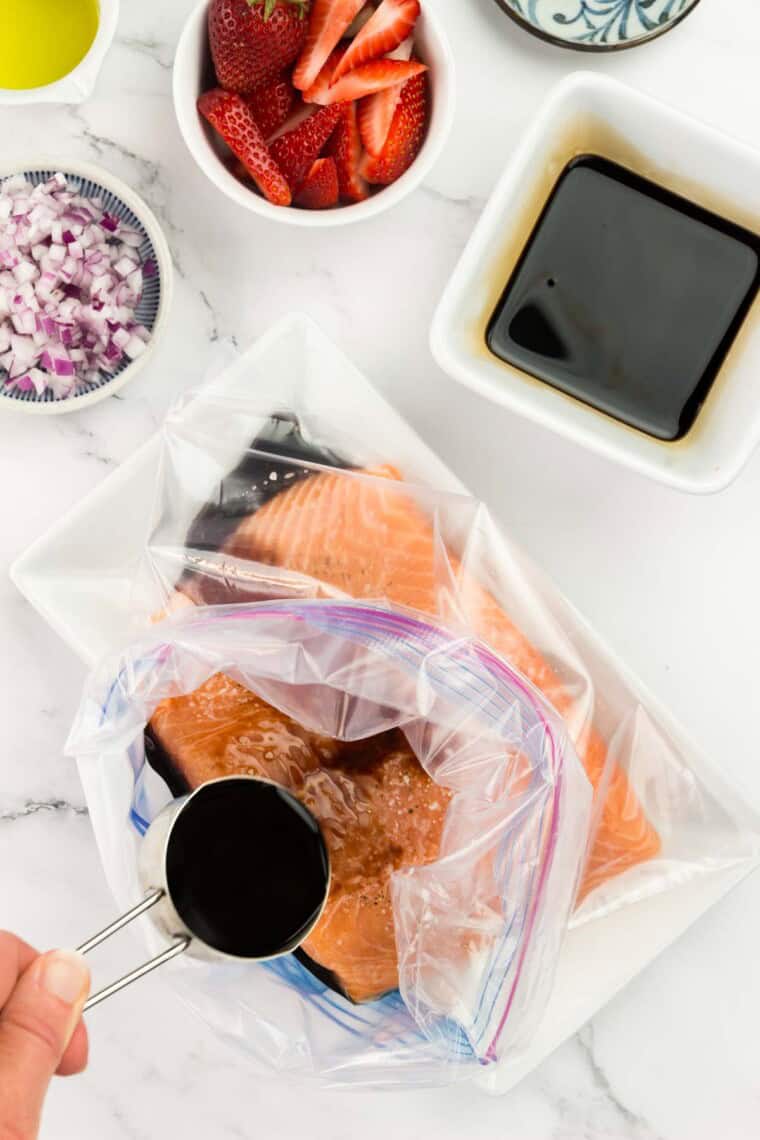 The marinade is added to salmon in a plastic bag.