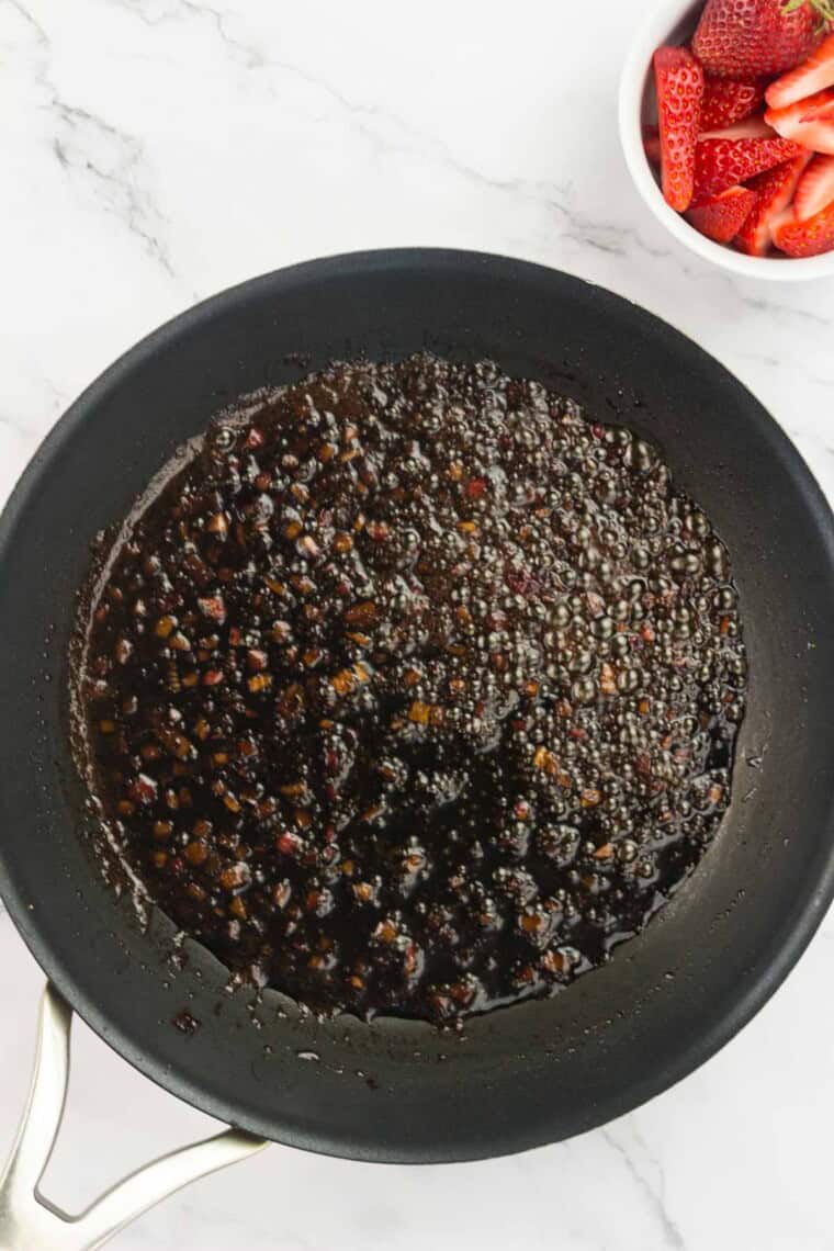 Balsamic vinegar cooks down in a pan.