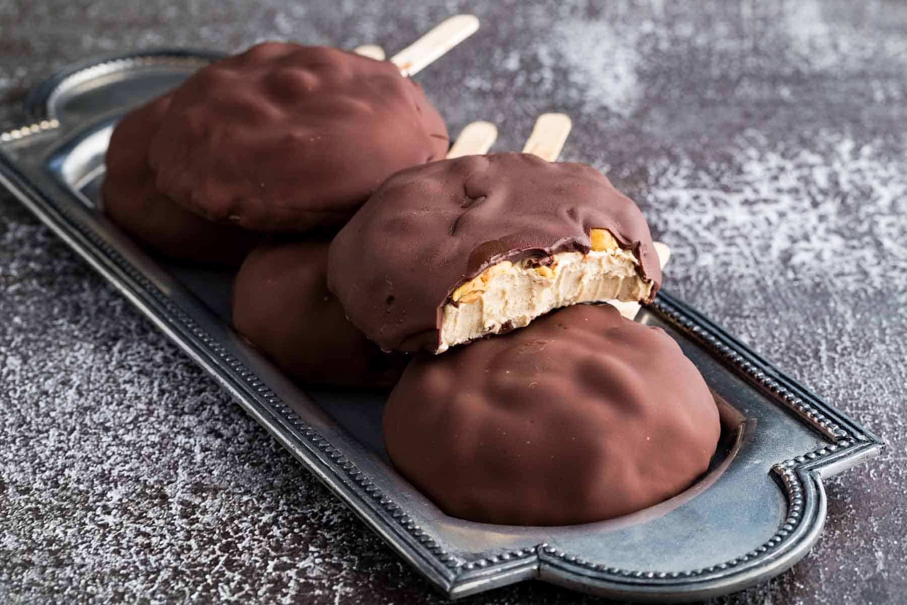 A serving tray holds peanut butter frozen yogurt bars covered in chocolate coating.