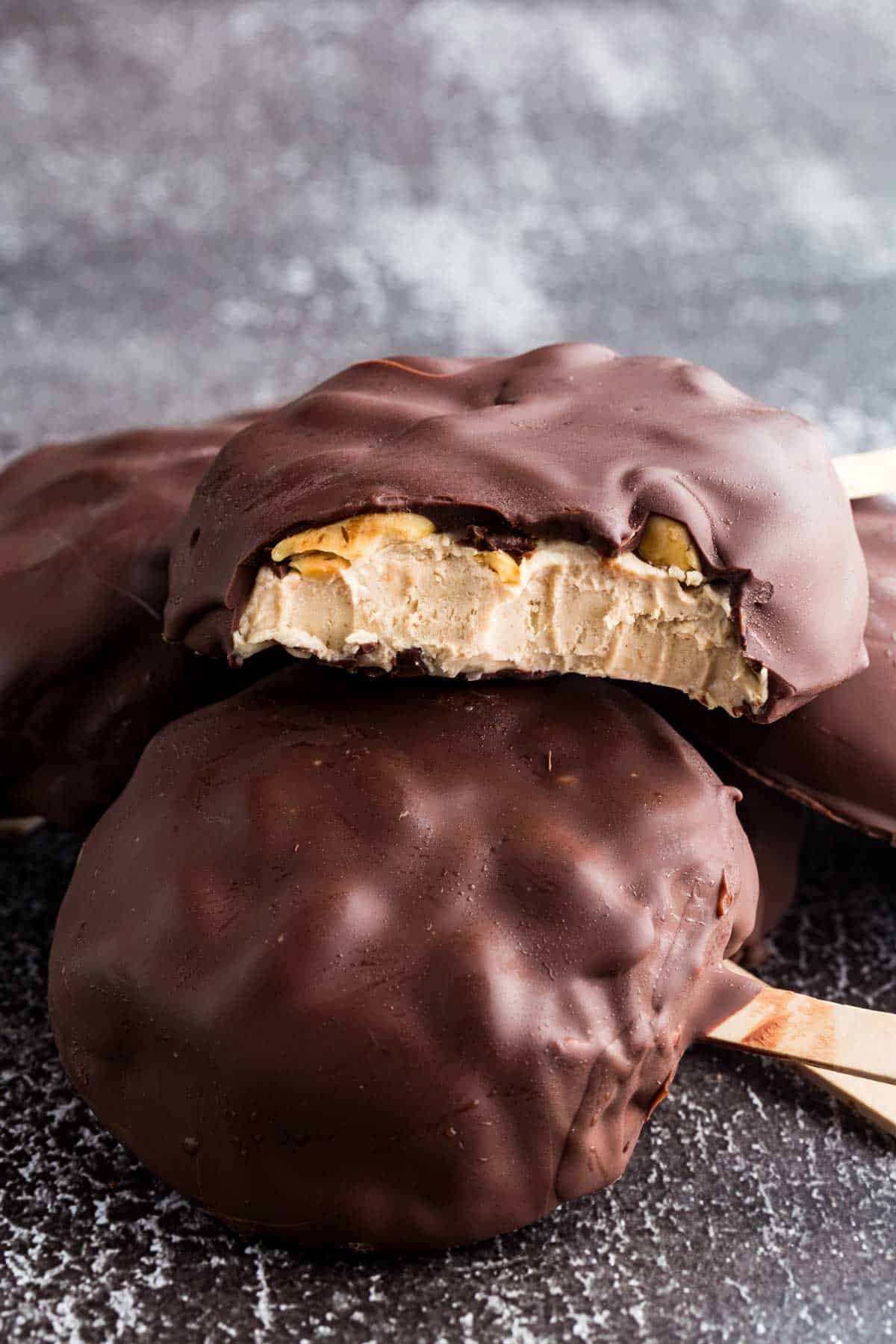 Peanut butter frozen yogurt bars encased in chocolate are stacked on top of each other.