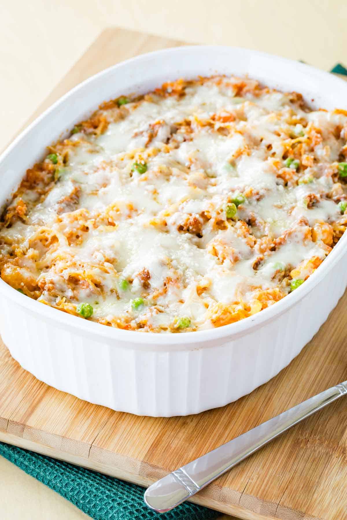 A baking dish of spaghetti squash casserole resting on a wooden board.